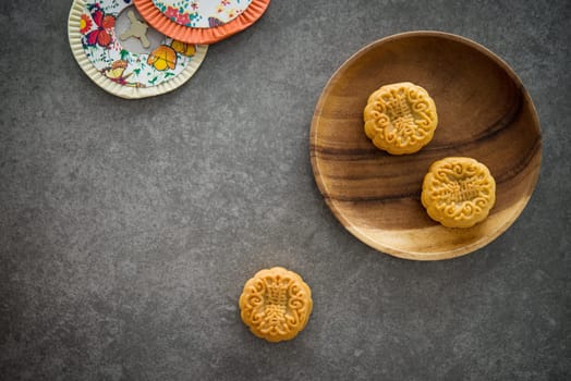 Traditional baked moon cakes is offered to friends or family during Mid-Autumn Festival. Flatlay table top view dark background with copy space. The Chinese character represent "lotus paste"""