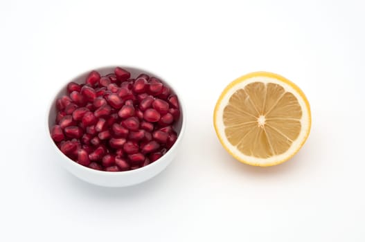 Yellow freshness lemon on a white background, seeds of pomegranates in a cup.