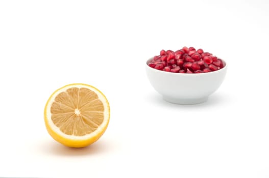 Lemon in the foreground and a pomegranate seeds in the background.