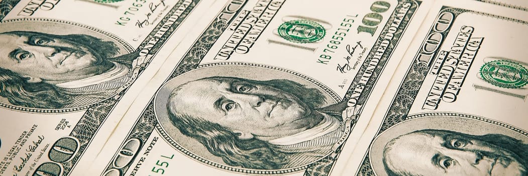 Denominations of one hundred dollars are arranged in a row. Processing under the antiquity. View at an angle.