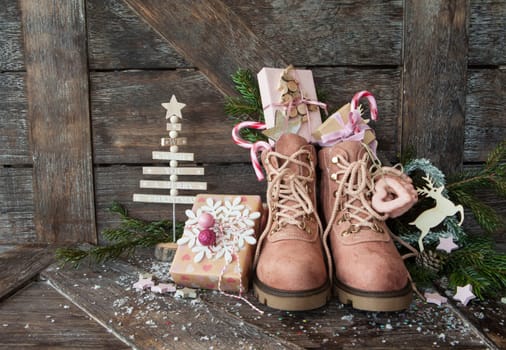 Rustic boots with christmas presents on wooden background
