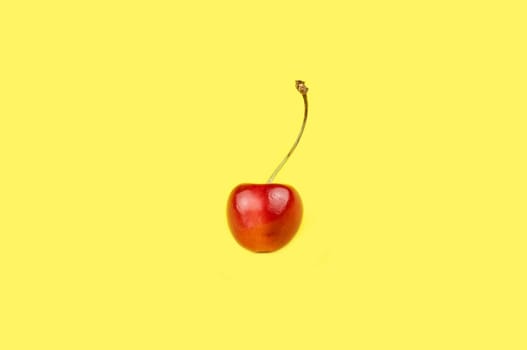 Ripe bright cherry on a yellow background.