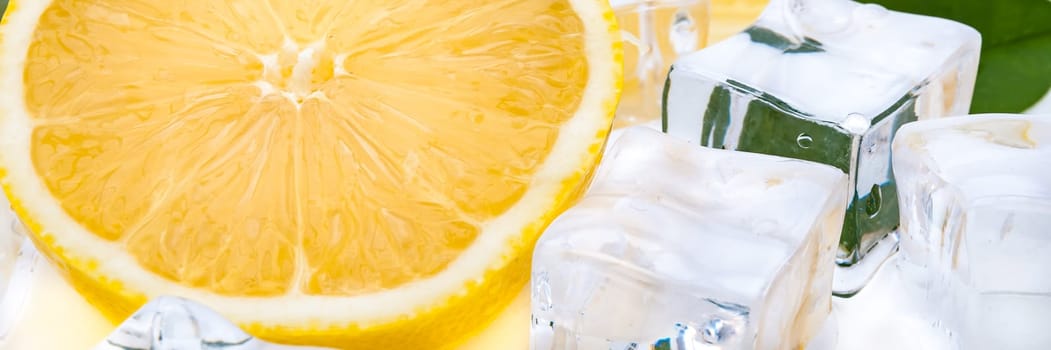 Half a juicy bright lemon and refreshing ice cubes close-up