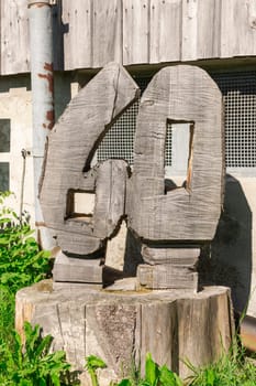 Number 60 carved from a tree stump in front of a barn in the grass.