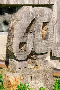 Number 60 carved from a tree stump in front of a barn in the grass.