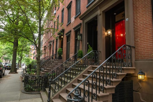 Row of old brownstone buildings along an empty sidewalk block in the Greenwich Village neighborhood of Manhattan, New York City, NYC, USA.