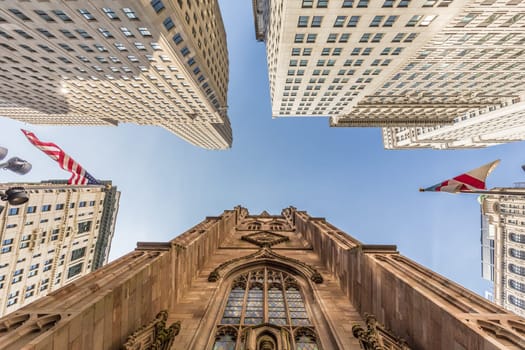 Wide angle upward view of Trinity Church at Broadway and Wall Street with surrounding skyscrapers, Lower Manhattan, New York City, USA.