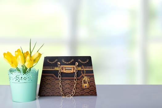 Bouquet yellow tulips and a brown gift paper bag on table in front of abstract colorful bright background. Space for your product display montage. Mother day, valentine or other holidays.