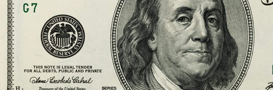 Part of the bill is one hundred US dollars. The left part. Close-up.