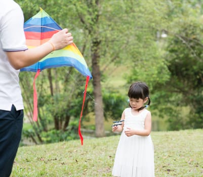 Asian family outdoors activity. Father and daughter flying kite at garden park.