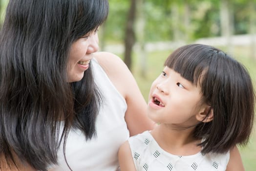 Happy mother and daughter bonding at green park. Asian family outdoors activity.