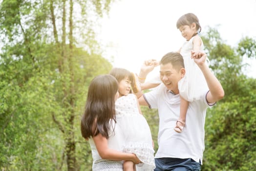Parents and children having fun at park. Asian family outdoors portrait.