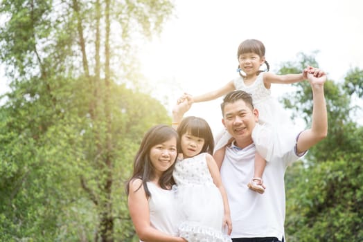 Parents and children looking camera at park. Asian family outdoors portrait.