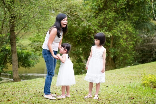 Mother comforting crying daughter at outdoor park. Asian family outdoors portrait.