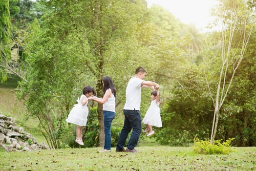 Asian family outdoors. Parents and children playing at garden park.