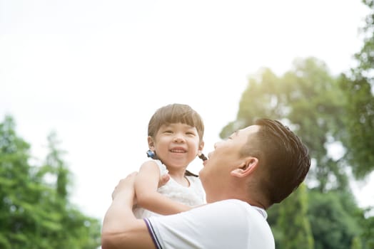Asian family outdoors portrait. Father and daughter playing at green park.