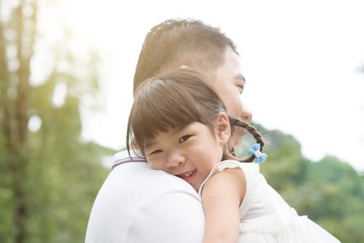 Asian family outdoors portrait. Father holding daughter at green park.