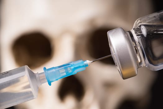 medical vials, syringe and blurry skull close up