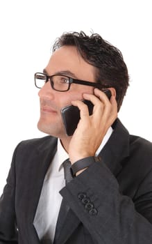 A handsome business man standing in a dark suit and black hair talking.on his cell phone, wearing grasses, isolated for white background.