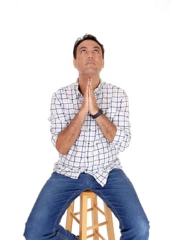 A tall handsome man sitting on a chair and folding his hands and .praying to God, looking up, isolated for white background.