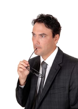 A close up image of a handsome business man standing in a dark suit.with his glasses in his mouth, black hair, isolated for white background.