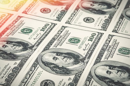 Denominations of one hundred dollars are arranged in a row. Glow in the corner. View at an angle. Isolated.