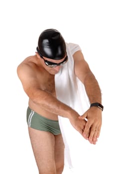 A tall handsome man in a green swimsuit showing how to jump into.the water with his swim google and cap isolated on white background.