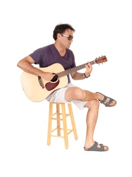 A handsome young man sitting in casual clothing playing his guitar.and singing for himself, isolated for white background.