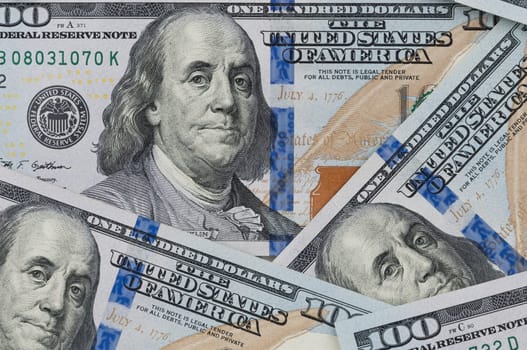 Denominations of one hundred US dollars. Spread out on the table. Not full visibility of notes.