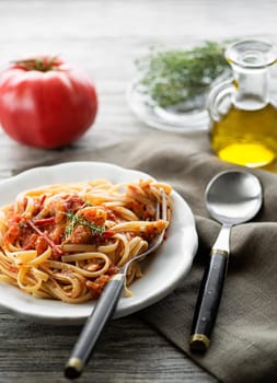 Delicious meal with spaghetti and tomato sauce served on wooden background