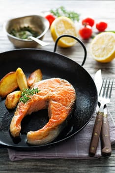 Meal with salmon fish and potatoes on wooden background
