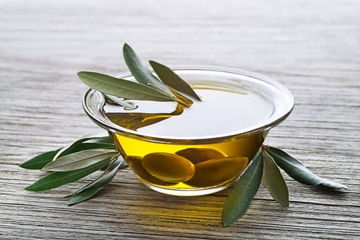 Bowl of virgin olive oil with olives close up