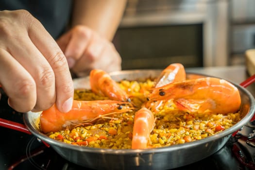 Chef is adding seafood to paella, close up