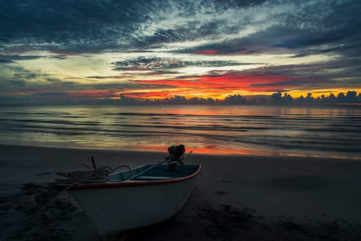 A beautiful dawn on a topical beach with a boat.