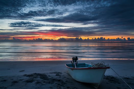 A beautiful tropical dawn with a boat on beach.