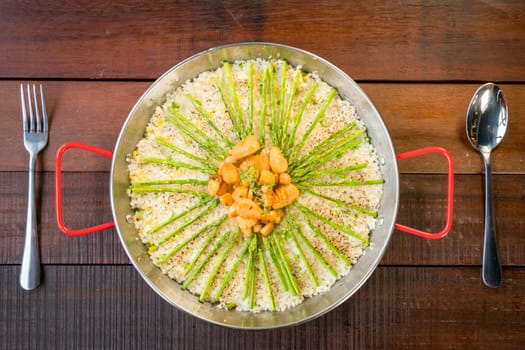 Paella with scallops and asparagus in traditional pan.
