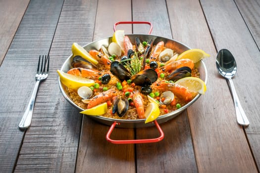 Paella with seafood vegetables and saffron served in the traditional pan.