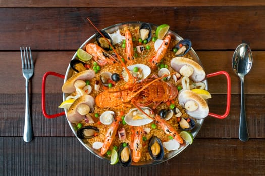 Gourmet seafood Valencia paella with fresh langoustine, clams, mussels and squid on savory saffron rice with prawn, scollops, mussels and lime slices, close up view
