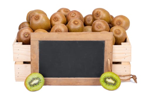 Wooden box filled with many ripe kiwi fruits and two half fruits and a old blank slate blackboard isolated on white background