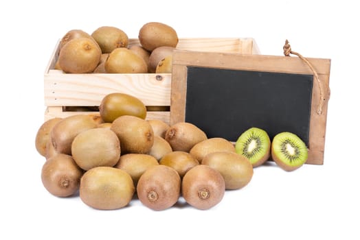 Wooden box filled with many ripe kiwi fruits and two half fruits and a old blank slate blackboard isolated on white background