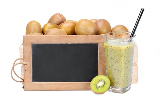 Wooden box with ripe kiwi fruits, a glass with kiwi smoothie and a old blank slate blackboard isolated on white background