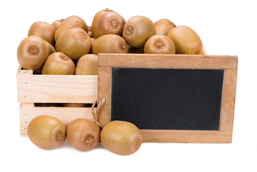 Wooden box filled with many ripe kiwi fruits and a old blank slate blackboard isolated on white background