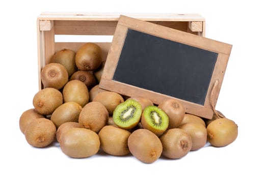 Wooden box filled with many ripe kiwi fruits and two half fruits and a old blank slate blackboard isolated on white background