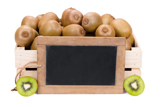 Wooden box filled with many ripe kiwi fruits and two half fruits and a old blank slate blackboard isolated on white background