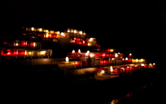 Bright lights of burning candles in the darkness of Christian church