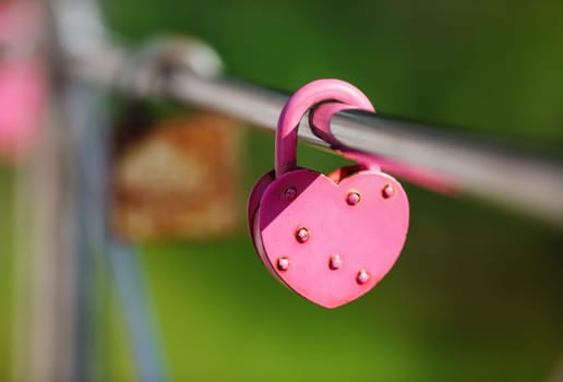 Closed pink heart shaped padlock. Symbol of eternal love. Tradition of lovers on the wedding day. Selective focus.