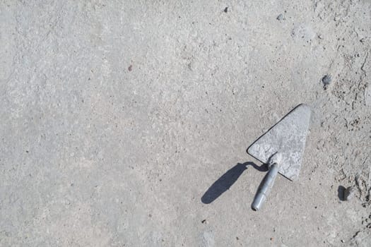 Old trowel on gray concrete background. Space for text. Flat lay.