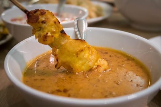 Malaysian chicken satay dip into delicious peanut sauce, one of famous local dishes.