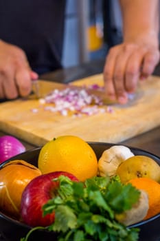 Fresh fruit in the kitchen with chef cutting onion to prepare food.