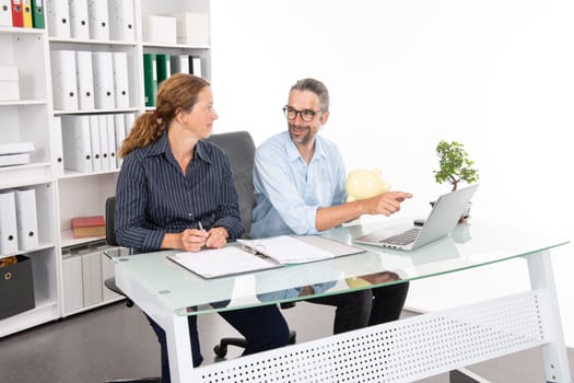 young businessman with piggy bank and businesswoman together in the office